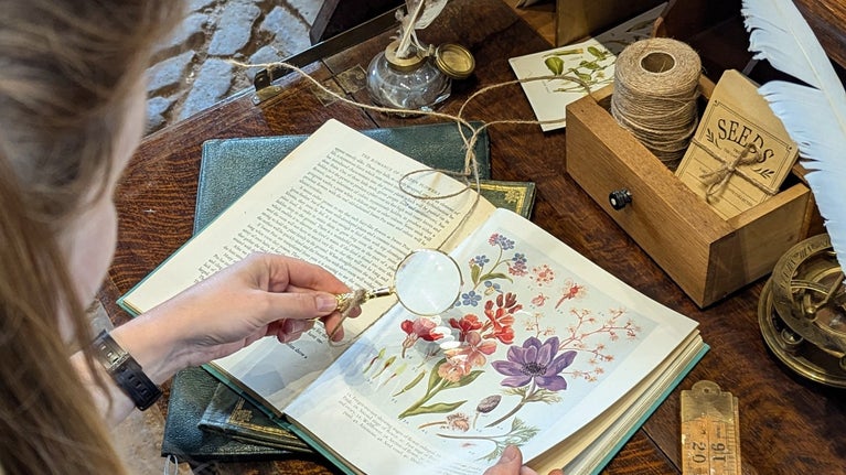 A visitor looking at a gardening book on an antique desk